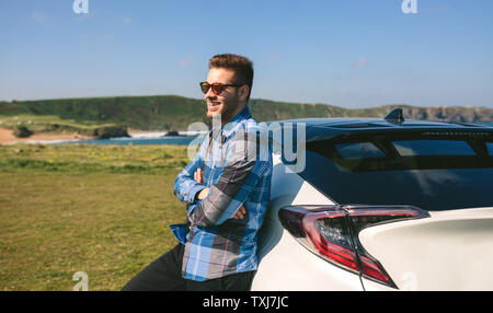 Jeune homme se penchant sur sa voiture Banque D'Images