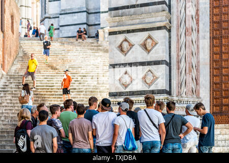 Sienne, Italie - 27 août 2018 les marches de la rue : allée de la vieille ville, village de la Toscane avec des gens touristes tour group walking dans les escaliers jusqu'à la célèbre église Banque D'Images