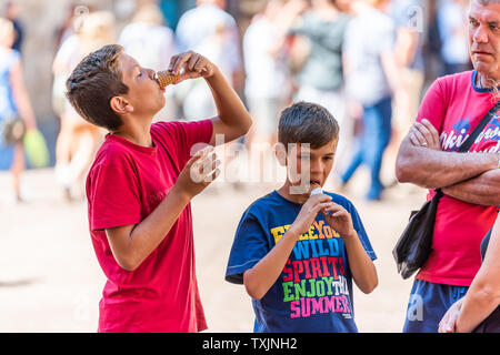 San Gimignano, Italie - 27 août 2018 : les jeunes enfants eating ice cream cone gelato sur place en petit village médiéval historique en Toscane par de célèbres Banque D'Images