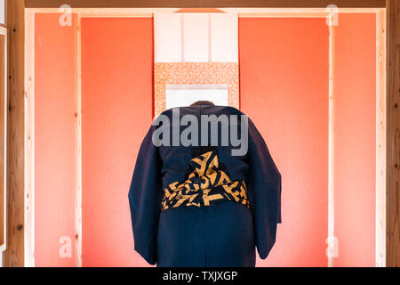 Chambre traditionnelle japonaise avec porte coulissante fenêtre et alcôve avec de la couleur rouge et faites défiler avec l'homme en kimono s'inclinant Banque D'Images