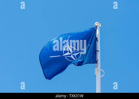 De brandir le drapeau de l'OTAN contre le vent en fond de ciel clair Banque D'Images