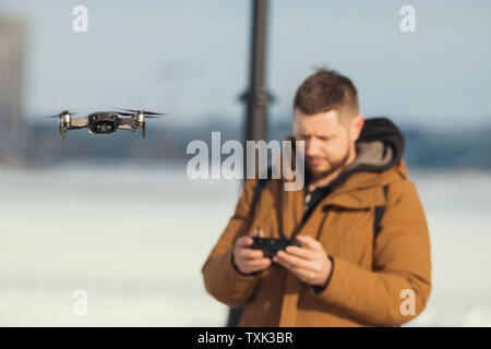 Un homme en jaune clothes holding une télécommande pour le drone - gérer le vol quadrocopter Banque D'Images