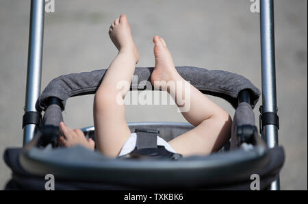 Bielefeld, Allemagne. 25 Juin, 2019. Un enfant s'étend ses jambes au-delà de la poignée de son landau. Le thermomètre affiche plus de 30 degrés Celsius en Westphalie orientale. Credit : Friso Gentsch/dpa/Alamy Live News Banque D'Images