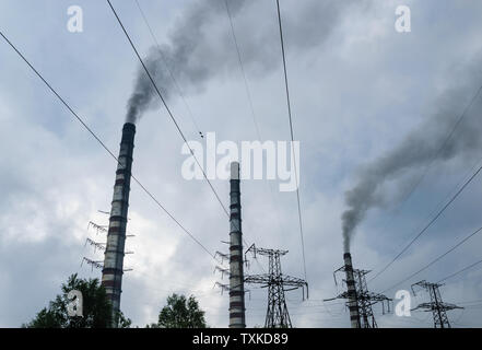 Les tuyaux des centrales thermiques émettent de la fumée. Tours haute tension et lignes électriques sur fond de nuages. Banque D'Images