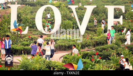 Les touristes chinois de visiter un parc d'amusement avec un géant 'Amour' afficher à Chongqing le 27 août 2010. Que la Chine s'ouvre à de plus en plus d'investissements internationaux, les entreprises et la culture, à la fois son paysage culturel et commercial est en train de changer pour refléter ces influences occidentales. UPI/Stephen Shaver Banque D'Images