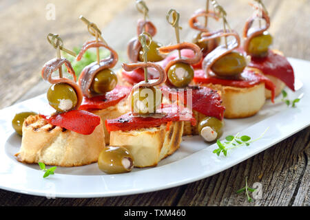 Pinchos espagnol : brochette de collations faits de pain grillé avec Poivrons et piments marinés, olives farcies et et sur le dessus les filets d'anchois Banque D'Images