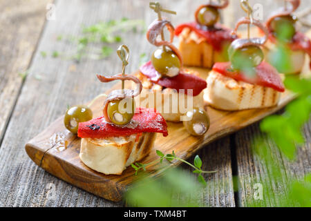Pinchos espagnol : brochette de collations faits de pain grillé avec Poivrons et piments marinés, olives farcies et sur le dessus les filets d'anchois Banque D'Images
