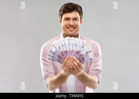 Smiling Young man with fan de euro argent plus de Gray Banque D'Images