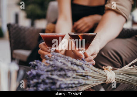 Date romantique les amoureux se tenant la main. à la table. Cocktail sur l'arrière-plan. Concept d'amour. Bouquets de lavande séchée sur l'arrière-plan Banque D'Images