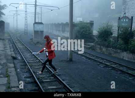 Une femme chinoise promenades pour un train à vapeur a la gare en Jiayang Shixi, une petite ville de montagne dans la province du Sichuan, le 9 avril 2016. Bien que bénéficiant de la plus longue et la plus moderne du système ferroviaire à grande vitesse avec plus de 19 000 km de voies, la Chine est également le dernier tournant passager à voie étroite de train à vapeur. Construit en 1958, le chemin de fer Jiayang a été construit pour transporter le charbon le long d'une piste de 13 km en utilisant des moteurs à vapeur construit dans les années 1950. Les mêmes moteurs sont encore en usage. Photo par Stephen Shaver/UPI Banque D'Images