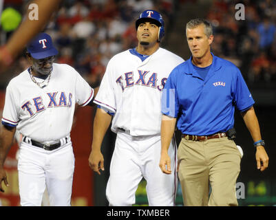 Les Rangers du Texas Nelson Cruz, avec manager Ron Washington, à gauche, et entraîneur Kevin Harmon, promenades retour à l'étang après sa blessure au tendon gauche en sixième manche contre le Los Angeles Algels au Rangers Ballpark in Arlington, Texas, le 28 août 2011. E Rangers a gagné 9-5 et maintenant un jeu trois plomb dans l'AL'Ouest. UPI/Ian Halperin Banque D'Images