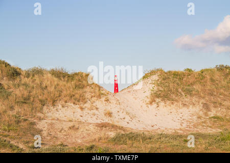 Voir entre deux dunes sur le phare rouge de l'île de Schiermonnikoog Néerlandais Banque D'Images