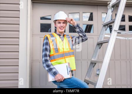Young male architect standing sur une échelle et vêtus de vêtements de sécurité. Banque D'Images