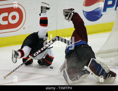 L'aile gauche des Sénateurs d'Ottawa, Antoine Vermette (L) survole l'Avalanche du Colorado le gardien Vitaly Kolesnik (R) dans la deuxième période à la Pepsi Center de Denver, Colorado, le 12 décembre 2005. Vermette a reçu une peine d'interférences gardien sur le jeu. Kolesnik est resté à plat sur la glace pendant plusieurs minutes avant de se lever apparemment indemne. (Photo d'UPI/Gary Caskey) Banque D'Images