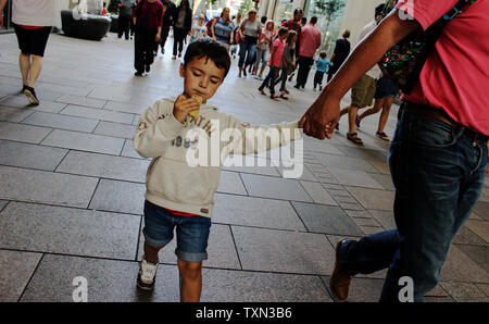 Juin 2019, Cardiff, Pays de Galles.Garçon enfant marche avec père tenant la main, manger de la pâtisserie dans la rue. Banque D'Images