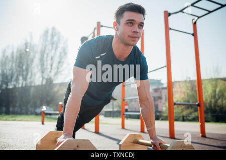La gymnastique au sport en plein air, jeune homme faire poussez se lève sur l'équipement d'exercice Banque D'Images