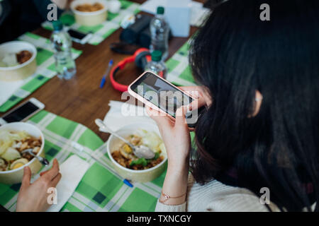 Young woman photographing repas au cafe table, plus d'épaule Banque D'Images