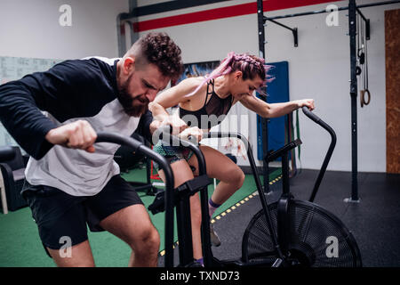 Jeune femme et l'homme s'entraîner au sport vélos d'exercice, d'action Banque D'Images