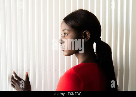 Jeune femme en tee-shirt rouge, la tête et l'épaule portrait de profil Banque D'Images