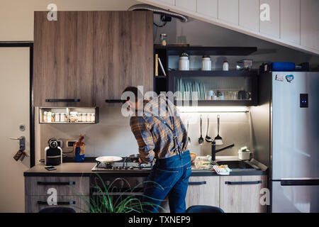 Mid adult man de préparer des aliments à cuisson cuisine, vue arrière Banque D'Images