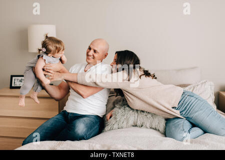 Mère et père sur lit de bébé fille de levage Banque D'Images