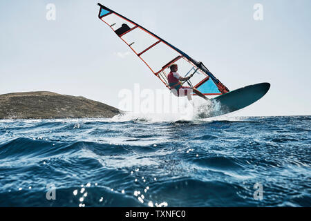 Jeune homme l'air tandis que la planche à voile, les vagues de l'océan, Limnos, Calino, Grèce Banque D'Images