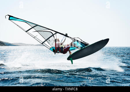 Jeune homme planche à voile au-dessus des vagues de l'océan, Limnos, Calino, Grèce Banque D'Images