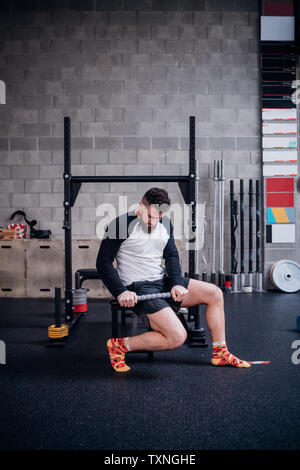 Jeune homme de cuisse avec rouleau de massage musculaire stick in gym Banque D'Images