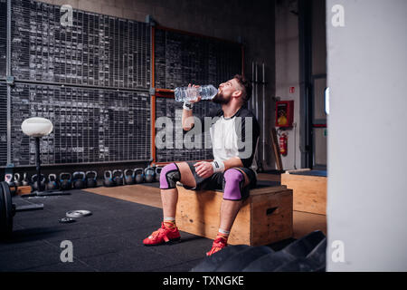 Jeune homme de l'eau potable dans une salle de sport Banque D'Images