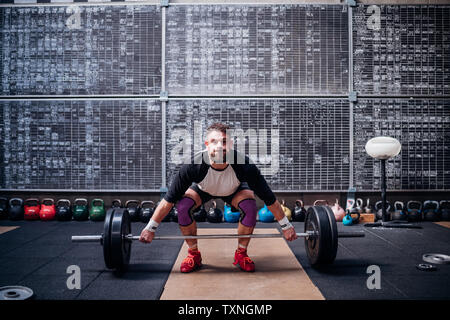 Jeune homme d'haltères de levage in gym Banque D'Images