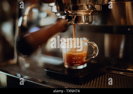 Barista pouring café frais en verre gradué sur machine à café de café, l'accent peu profondes Banque D'Images