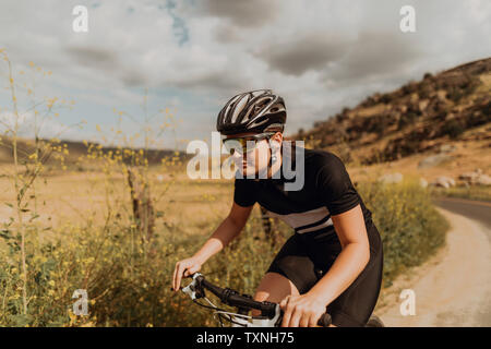 Jeune femme vélo cycliste on rural Road, Exeter, California, USA Banque D'Images