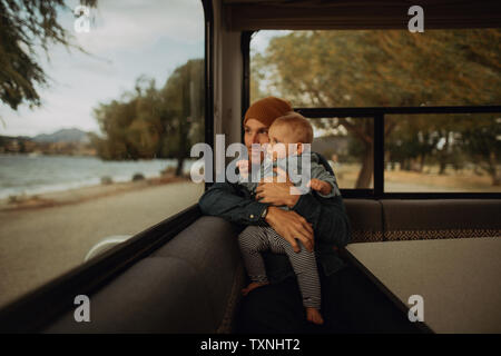 Father and baby looking out window de camping, Taranaki, Wanaka, Nouvelle-Zélande Banque D'Images