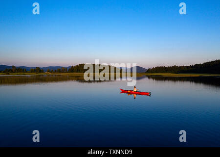 Vue arrière de l'antenne de femme athlétique kayak au coucher du soleil sur le lac de Cerknica, Slovénie, prises par drone. Banque D'Images