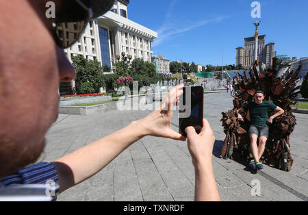 Kiev, Ukraine. 25 Juin, 2019. Prendre des photos des gens assis sur le trône de fer installé à la place de l'Indépendance à Kiev, Ukraine, le 25 juin 2019. ''Le Trône de fer de l'Est'' faites par des bénévoles de l'armée de Denys de Bushtets les pièces d'armures, active MBT une épave, des débris de véhicules, des missiles et des courroies de la cartouche a été exposé dans des flacons de la capitale de l'Ukraine pour rappeler aux habitants de la ville de la guerre. Credit : Sergii Kharchenko/ZUMA/Alamy Fil Live News Banque D'Images