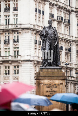 Les gens des parasols près de la statue du duc de Devonshire, Ave des Horse Guards, Whitehall, Westminster, London, UK. Banque D'Images