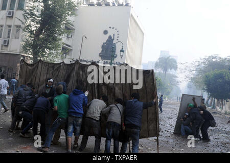 Des manifestants égyptiens contre le régime militaire se couvrir lors d'affrontements avec des soldats et leurs partisans au Caire le 16 décembre 2011. Les troupes égyptiennes se sont heurtés à des jets de cocktails Molotov contre des manifestants au Caire, comme la pire violence en semaines éclipsé le compte dans la deuxième phase d'une importante élection générale. UPI/ Mohamad Hosam Banque D'Images