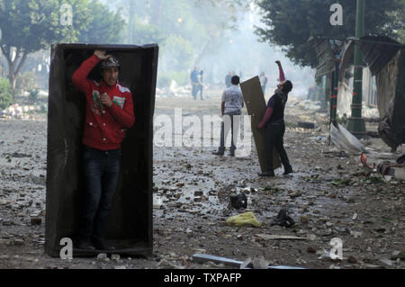 Des manifestants égyptiens contre le régime militaire se couvrir lors d'affrontements avec des soldats et leurs partisans au Caire le 16 décembre 2011. Les troupes égyptiennes se sont heurtés à des jets de cocktails Molotov contre des manifestants au Caire, comme la pire violence en semaines éclipsé le compte dans la deuxième phase d'une importante élection générale. UPI/ Mohamad Hosam Banque D'Images