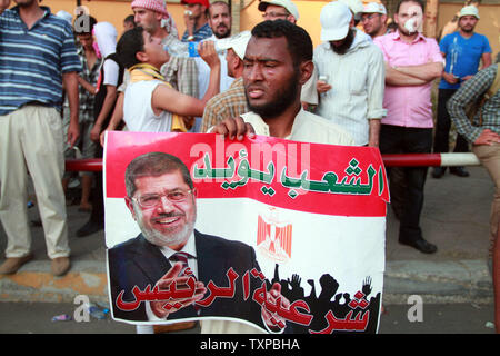 Les supporters égyptiens des Frères musulmans tenir photos du président déchu Mohamed Morsi comme ils crier des slogans à Rabia al-Adawiyya Square au cours d'une manifestation à la suite du coup d'État au Caire, Egypte le 5 juillet 2013. Tournage pouvait être entendu à la fois par la Garde républicaine et les rangs des manifestants. UPI/Ahmed Jomaa Banque D'Images