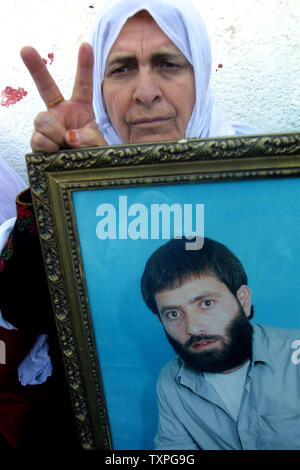 Les palestiniens détiennent des photos de leurs proches, à une manifestation organisée à l'extérieur du bâtiment de la Croix-Rouge internationale le 26 janvier 2004, dans la ville de Gaza, la bande de Gaza. Israël et le Liban le Hezbollah militant du groupe est parvenu à un accord d'échange de prisonniers dont l'état juif va libérer 23 Libanais, 12 400 prisonniers palestiniens et arabes. Le Hezbollah va libérer un homme d'affaires israélien et trois soldats. Kanatar, qui a été dans une prison israélienne depuis 1979, seront publiés dans un stade ultérieur, après qu'Israël reçoit des informations sur l'aviateur israélien Ron Arad dont l'avion s'est abattu sur le Liban en 1986 Banque D'Images