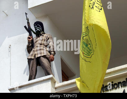 Un de militants palestiniens masqués de la Brigade des martyrs d'Al-Aqsa monte la garde sur le balcon de l'immeuble le gouvernorat de Khan Younis à Khan Younis dans le sud de la bande de Gaza le 24 juillet 2004. Quelque 20 militants ont repris le bâtiment pendant plusieurs heures, exigeant que leurs licenciements de sécurité postes être annulées, un membre du groupe a déclaré. Ils ont quitté le bâtiment après avoir reçu des promesses à résoudre le problème de ceux qui ont été tirés. Le groupe militant est affilié avec le dirigeant palestinien Yasser Arafat, faction du Fatah, mais ses membres les plus jeunes ont été irrités par la monopolisation du pouvoir Banque D'Images