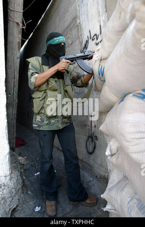 Un militant palestinien du Hamas montres pour approcher les forces israéliennes de derrière un sac de sable en position défensive à l'intérieur du camp de réfugiés de Jabaliya, le 5 octobre 2004 dans la bande de Gaza. Les militants palestiniens continuent de mettre en place la résistance contre les forces israéliennes, qui en sont à leur sixième jour d'une opération pour créer une zone tampon pour empêcher les militants de tirer des roquettes Qassam sur des villes frontalières et les villes le long de la frontière de Gaza.(UPI Photo/ Ismael Mohamad) Banque D'Images