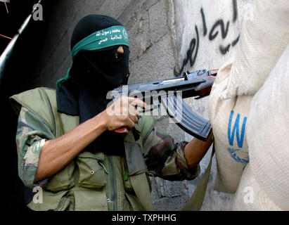 Un militant palestinien du Hamas montres pour approcher les forces israéliennes de derrière un sac de sable en position défensive à l'intérieur du camp de réfugiés de Jabaliya, le 5 octobre 2004 dans la bande de Gaza. Les militants palestiniens continuent de mettre en place la résistance contre les forces israéliennes, qui en sont à leur sixième jour d'une opération pour créer une zone tampon pour empêcher les militants de tirer des roquettes Qassam sur des villes frontalières et les villes le long de la frontière de Gaza.(UPI Photo/ Ismael Mohamad) Banque D'Images