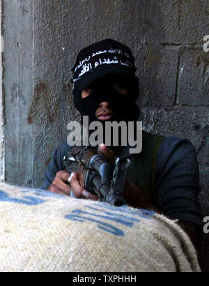 Un militant palestinien montres pour approcher les forces israéliennes de derrière un sac de sable en position défensive à l'intérieur du camp de réfugiés de Jabaliya, le 5 octobre 2004 dans la bande de Gaza. Les militants palestiniens continuent de mettre en place la résistance contre les forces israéliennes, qui en sont à leur sixième jour d'une opération pour créer une zone tampon pour empêcher les militants de tirer des roquettes Qassam sur des villes frontalières et les villes le long de la frontière de Gaza. (UPI Photo/ Ismael Mohamad) Banque D'Images