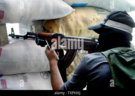 Un militant palestinien montres pour approcher les forces israéliennes de derrière un sac de sable en position défensive à l'intérieur du camp de réfugiés de Jabaliya, le 5 octobre 2004 dans la bande de Gaza. Les militants palestiniens continuent de mettre en place la résistance contre les forces israéliennes, qui en sont à leur sixième jour d'une opération pour créer une zone tampon pour empêcher les militants de tirer des roquettes Qassam sur des villes frontalières et les villes le long de la frontière de Gaza.(UPI Photo/ Ismael Mohamad) Banque D'Images