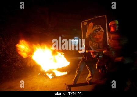 Les garçons palestiniens détiennent des posters de Yasser Arafat, lors d'une manifestation dans le camp de réfugiés de Rafah, dans le sud de la bande de Gaza, le 9 novembre 2004, à l'appui de leur leader en difficulté. L'état d'Arafat est considérablement dégradée du jour au lendemain par son coma approfondi, mais le ministre palestinien des affaires étrangères Nabil Shaath a dit qu'il est "toujours en vie" et son cerveau, le cœur et les poumons fonctionnent. (Photo d'UPI/Ismael Mohamad) Banque D'Images