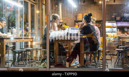 Les clients travailler et profiter de la connexion Wi-Fi gratuite dans un café à Chelsea à New York le mardi, Juin 18, 2019. Le wi-fi et les tables communes encouragent l'utilisation de la cafétéria comme un espace de co-working. (© Richard B. Levine) Banque D'Images