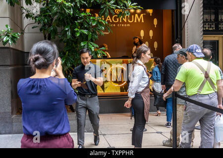 Les amateurs de crème glacée l'étape jusqu'à une fenêtre de Saks Fifth Avenue à New York qui a le verre supprimé et n'est transformé en un "glacier" pour la bonne humeur Co.'s Magnum mini-bar give-away le mardi 18 juin, 2019. Magnum, qui est une marque de bonne humeur, ce qui en soi est administré par le conglomérat géant Unilever, a donné un mini-barre de crème glacée Magnum produits dans différentes saveurs dans la promotion de l'événement. (© Richard B. Levine) Banque D'Images