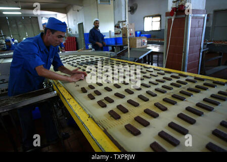 Employés palestiniens inspecter biscuits au chocolat à l'usine Al-Awda à Deir al-Balah, dans le centre de Gaza le 17 septembre 2007. L'usine, la production de biscuits faits que localement dans les territoires palestiniens, des visages fermeture possible en raison du manque de matières premières et de la difficulté à distribuer des marchandises à travers les terminaux pilotés israélienne crossing à la Cisjordanie. (Photo d'UPI/Ismael Mohamad) Banque D'Images