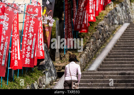 Nara, Japon - 14 Avril 2019 : retour de personnes femme marche marches des escaliers avec des drapeaux rouges bannières à Temple Kofuku-ji dans la ville Banque D'Images